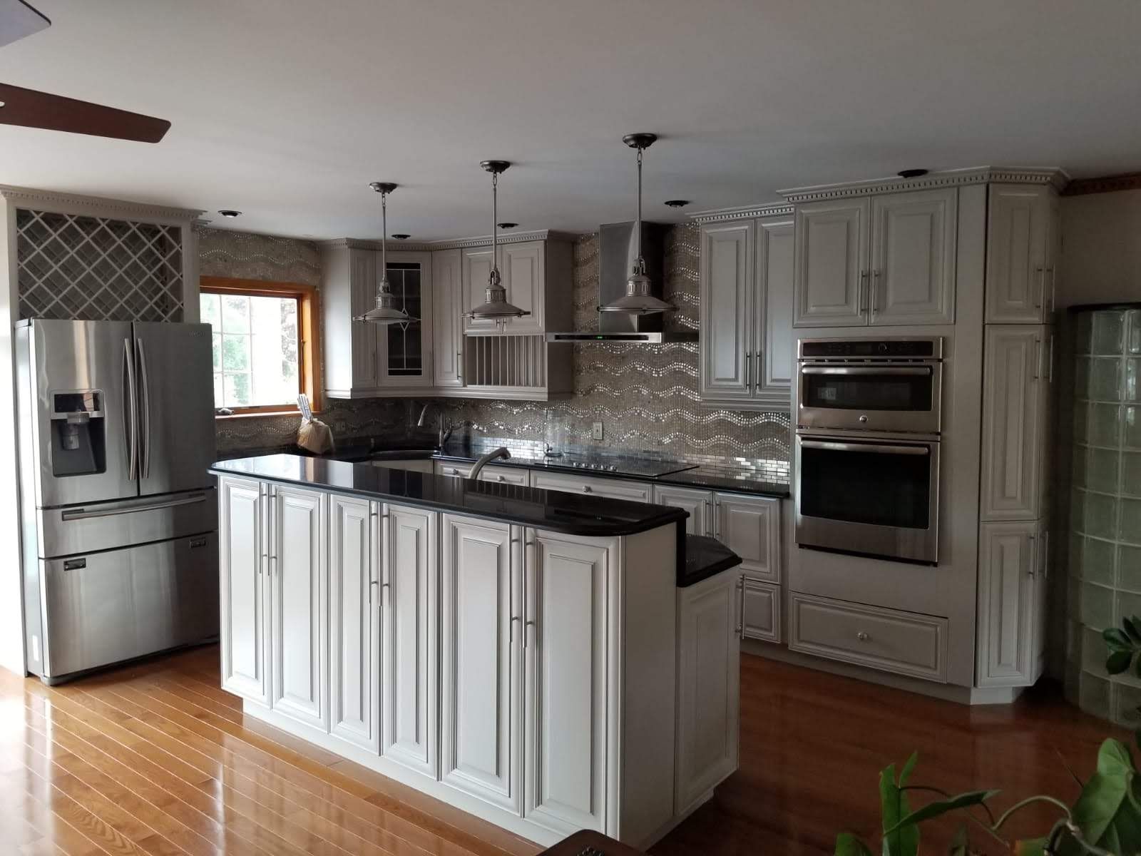 A kitchen with white cabinets, stainless steel appliances and a large island.