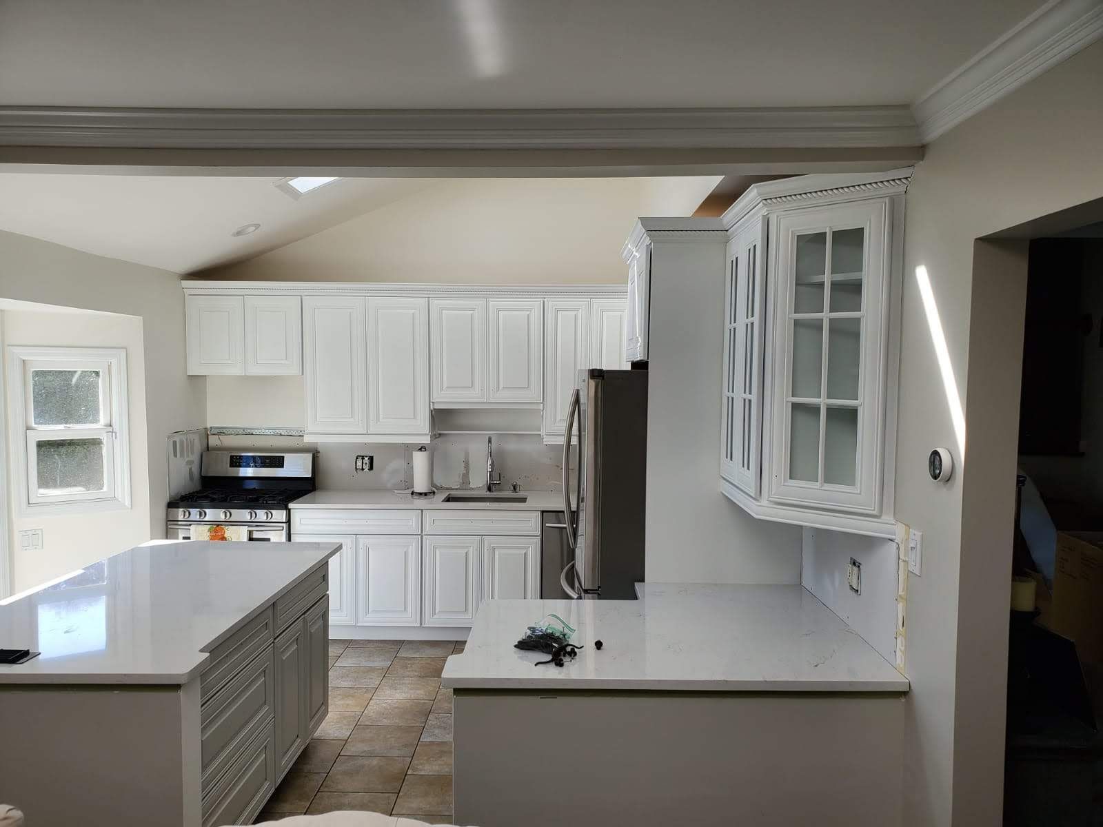 A kitchen with white cabinets, stainless steel appliances, and a large island.