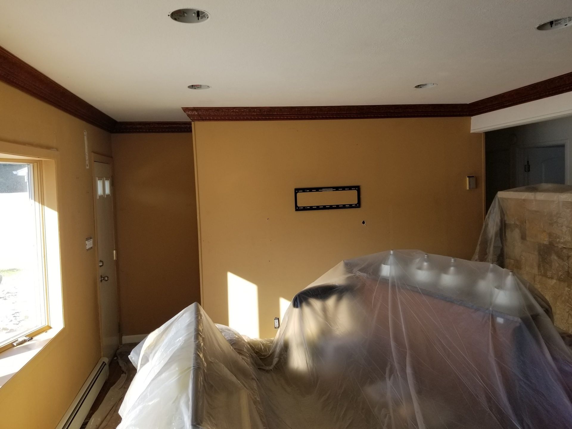 A room with a tv mounted on the wall is covered in plastic.
