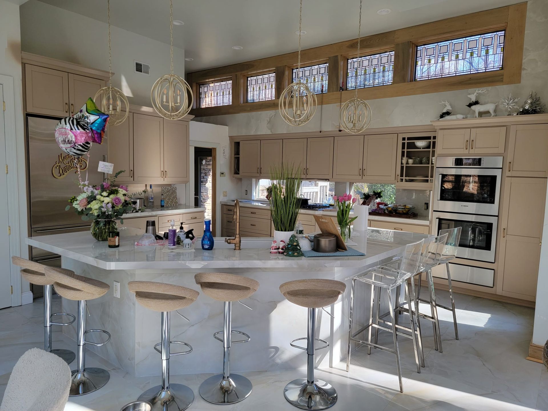 A kitchen with a large island and stools and a balloon hanging from the ceiling.