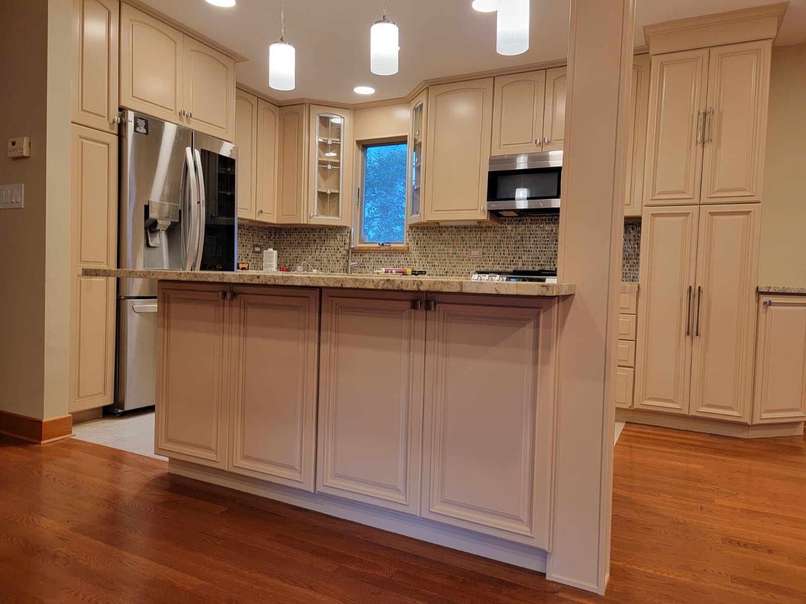 A kitchen with white cabinets, stainless steel appliances, and hardwood floors.