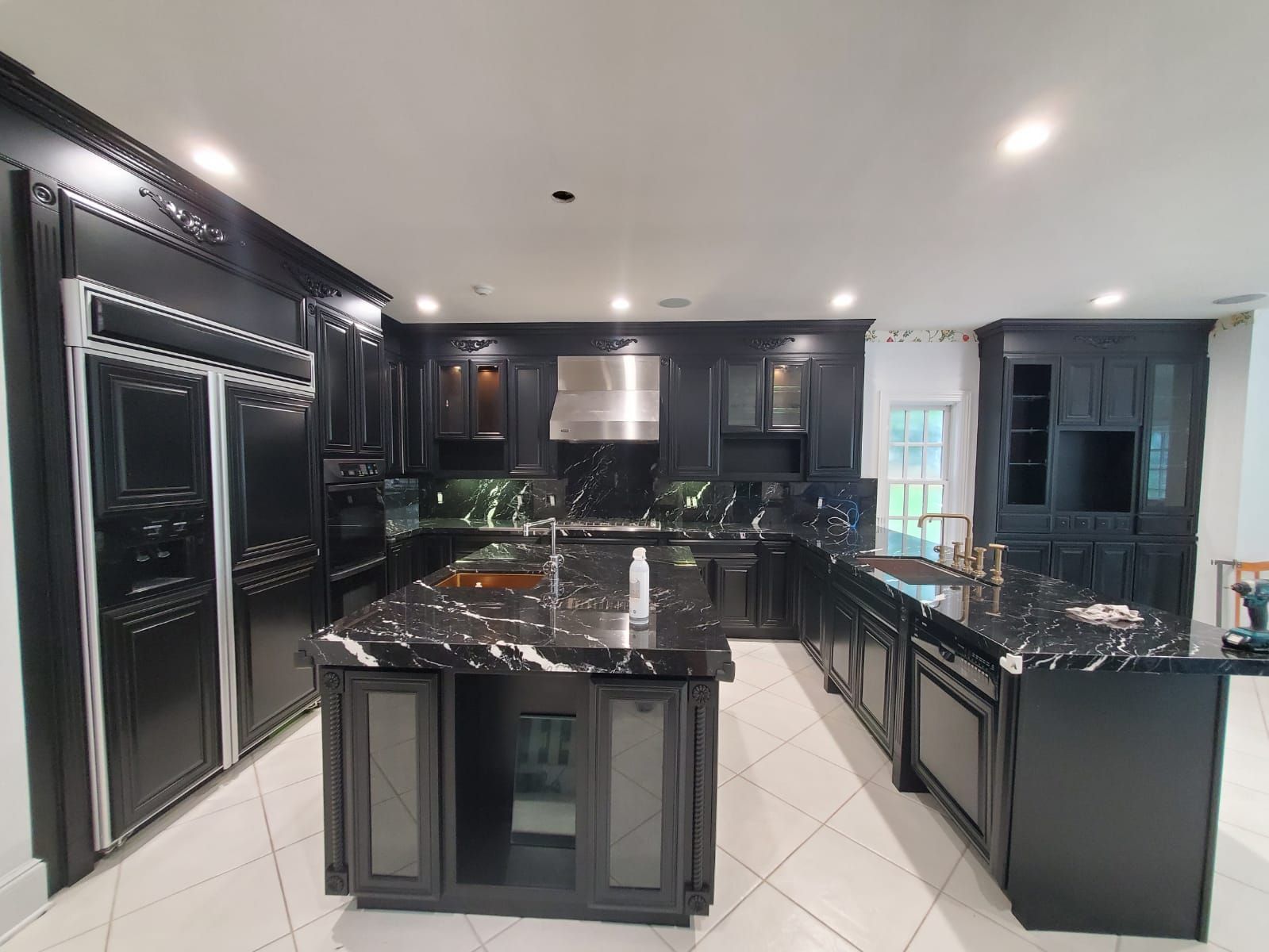 A kitchen with black cabinets, granite counter tops, and stainless steel appliances.