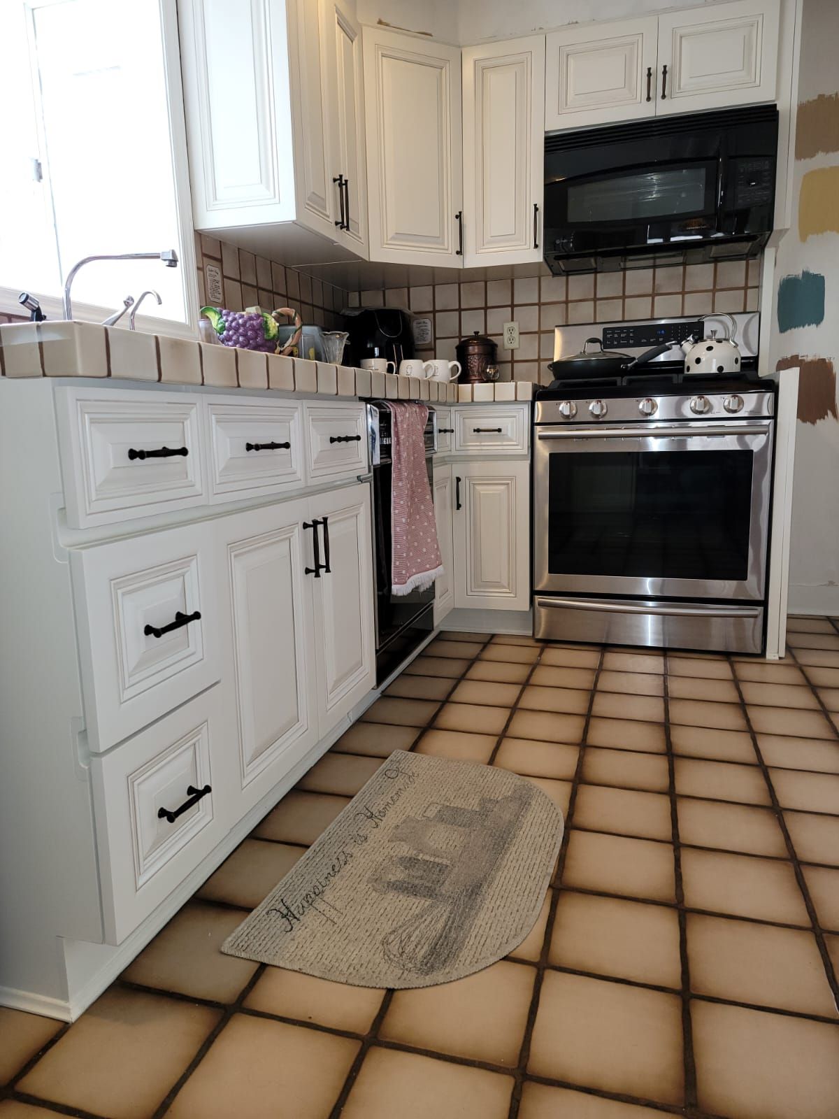 A kitchen with white cabinets and a rug on the floor