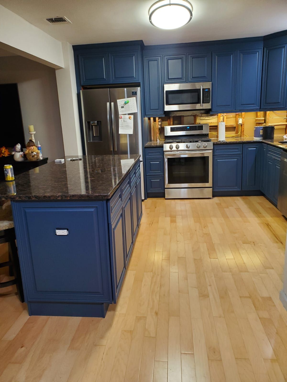 A kitchen with blue cabinets, stainless steel appliances, granite counter tops and hardwood floors.