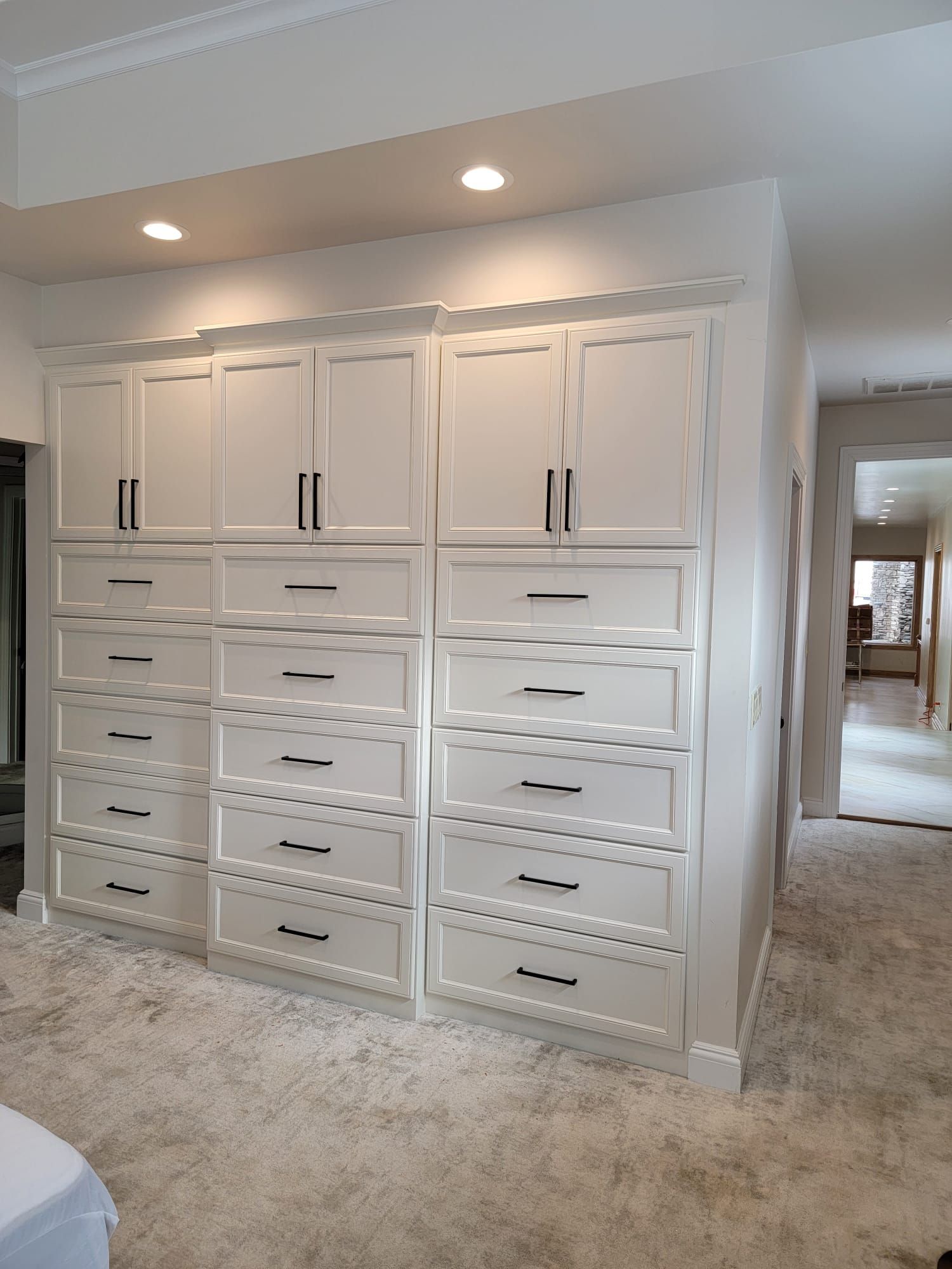 A bedroom with lots of white cabinets and drawers.