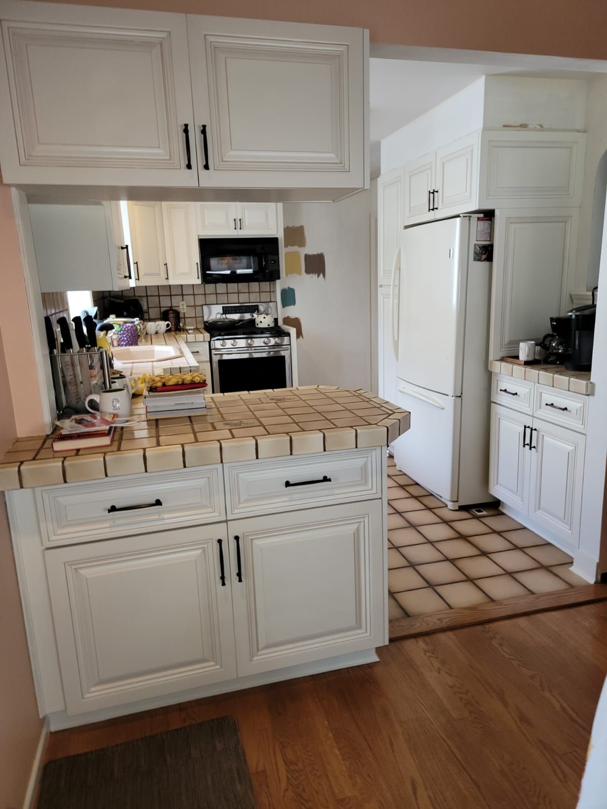 A kitchen with white cabinets, a refrigerator, a stove and a sink.