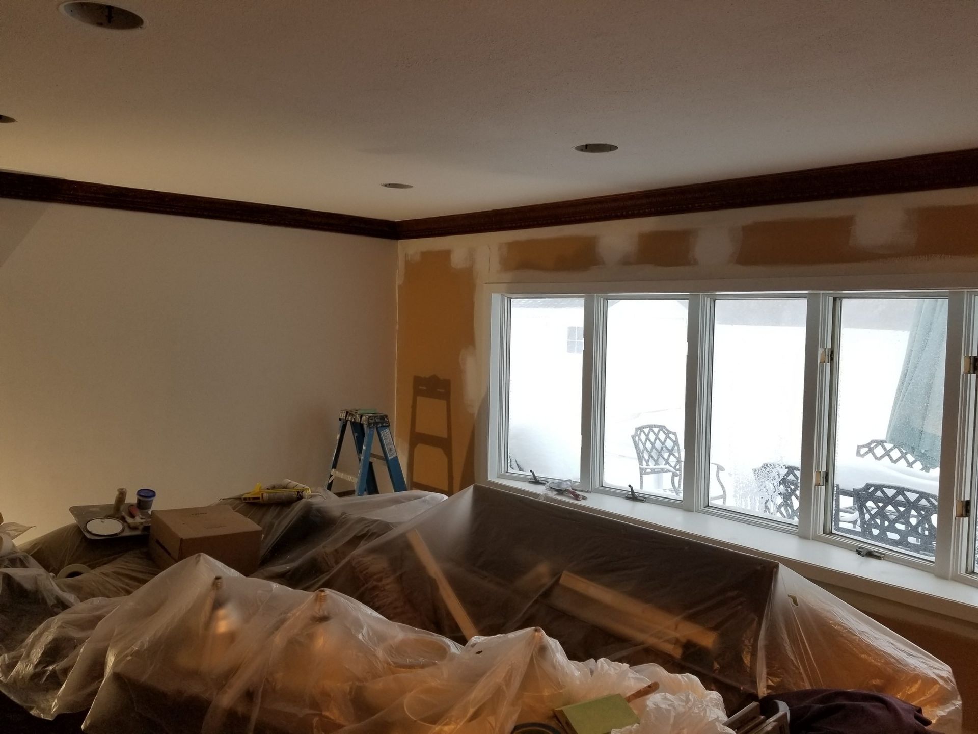 A living room is being painted with a ladder in the background.