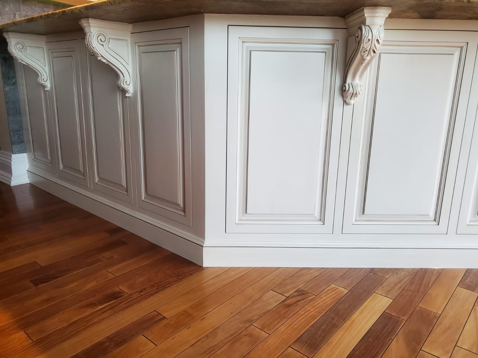 A kitchen island with white cabinets and wooden floors.