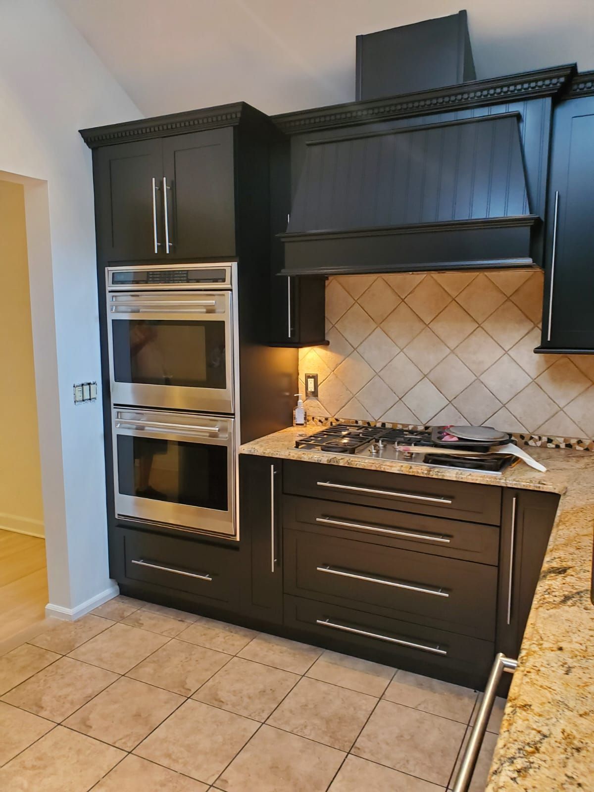 A kitchen with black cabinets and stainless steel appliances.