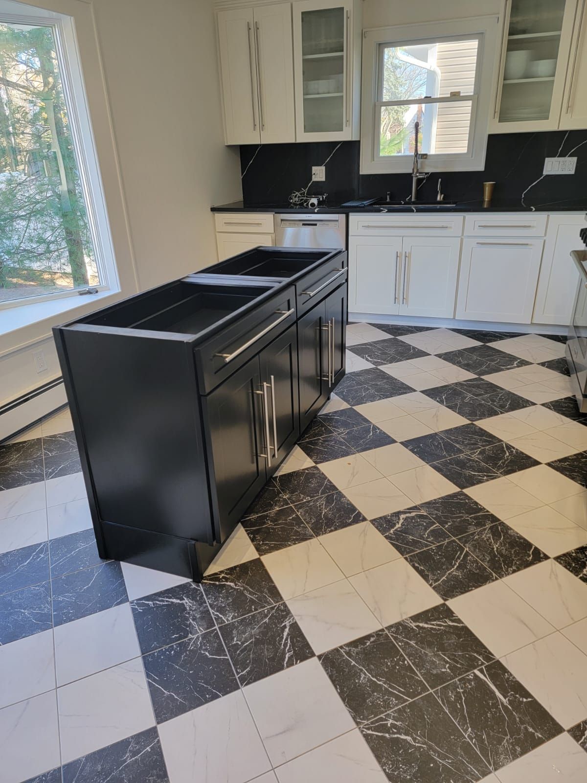 A kitchen with black cabinets and a checkered floor.