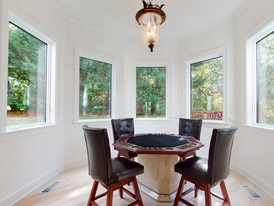A room with a table and chairs and lots of windows
