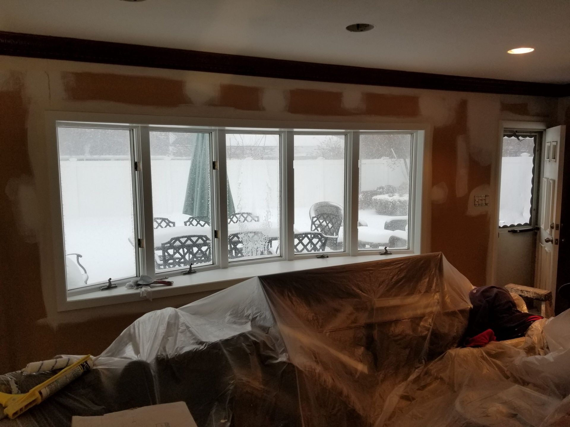 A living room with a couch and a window covered in plastic.