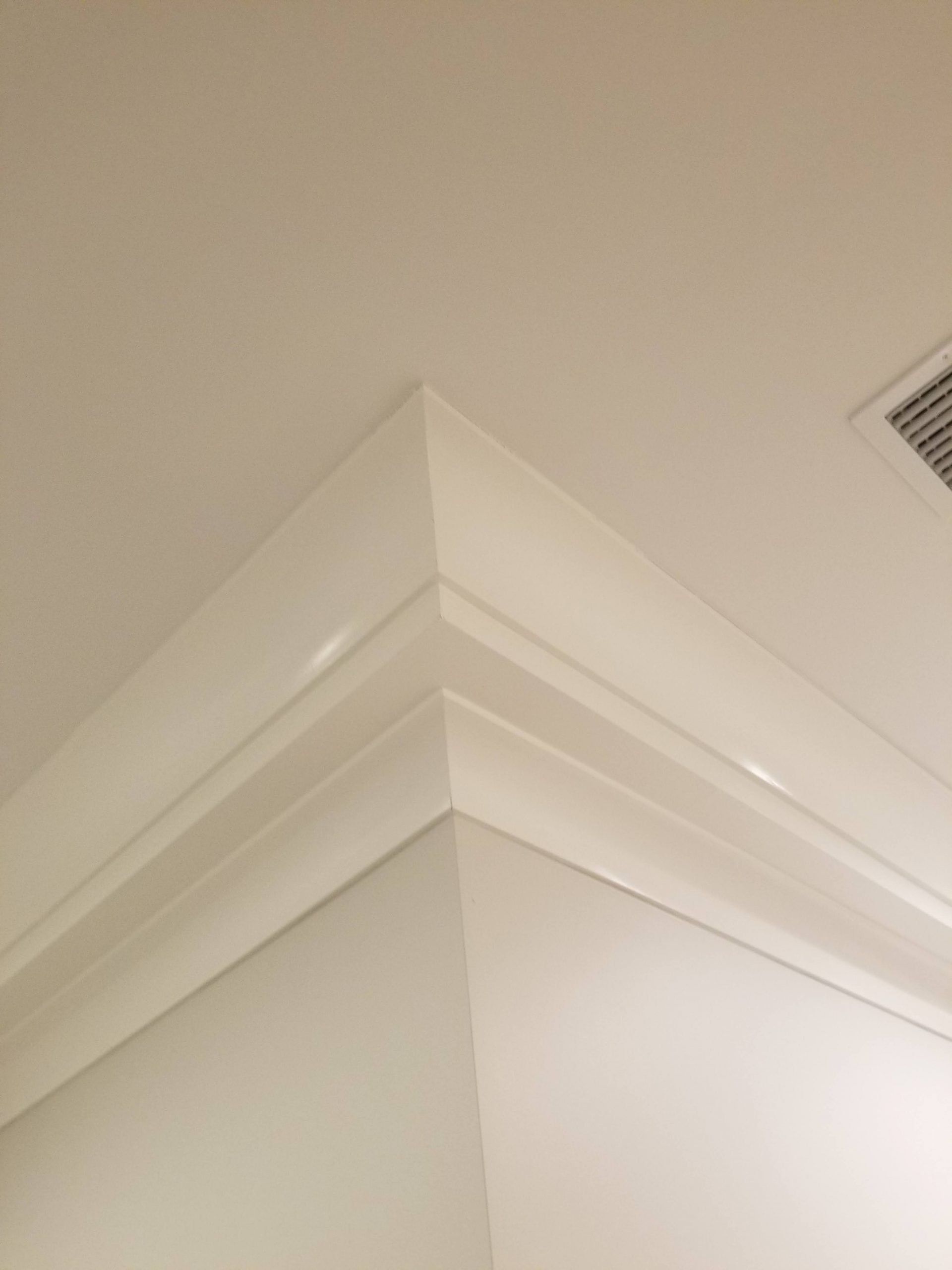 A close up of a white molding on the corner of a wall.