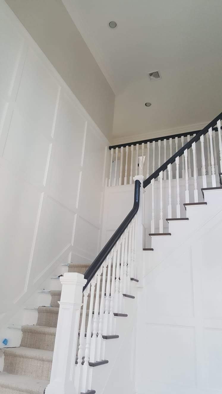 A white staircase with a black railing in a house.