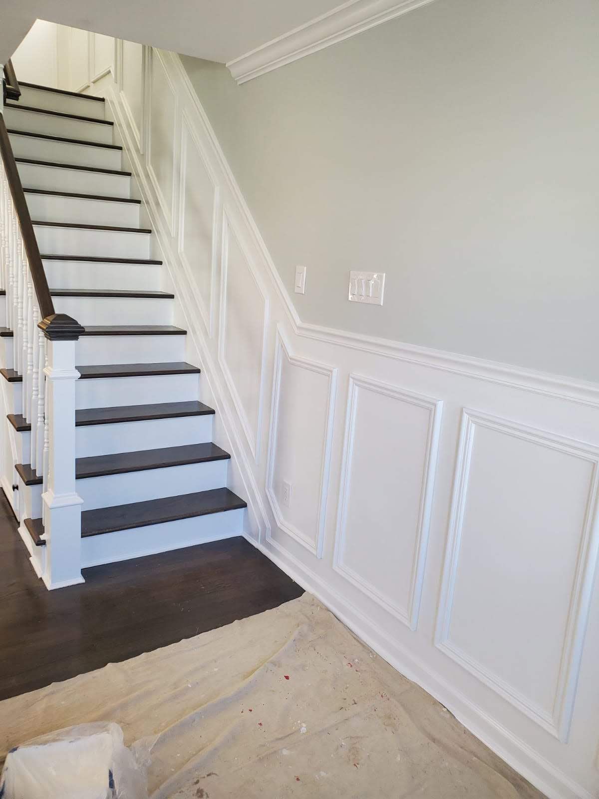 A white staircase with black steps and a wooden railing in a house.