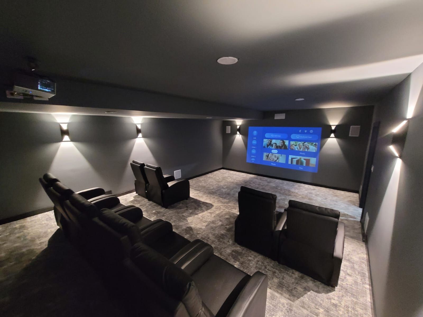 A home theater with black chairs and a projector screen.