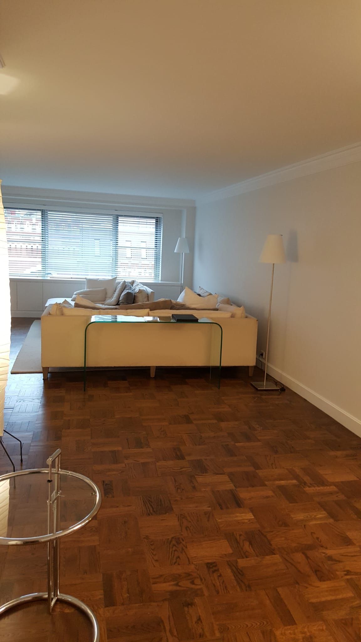 A living room with a white couch and a wooden floor.