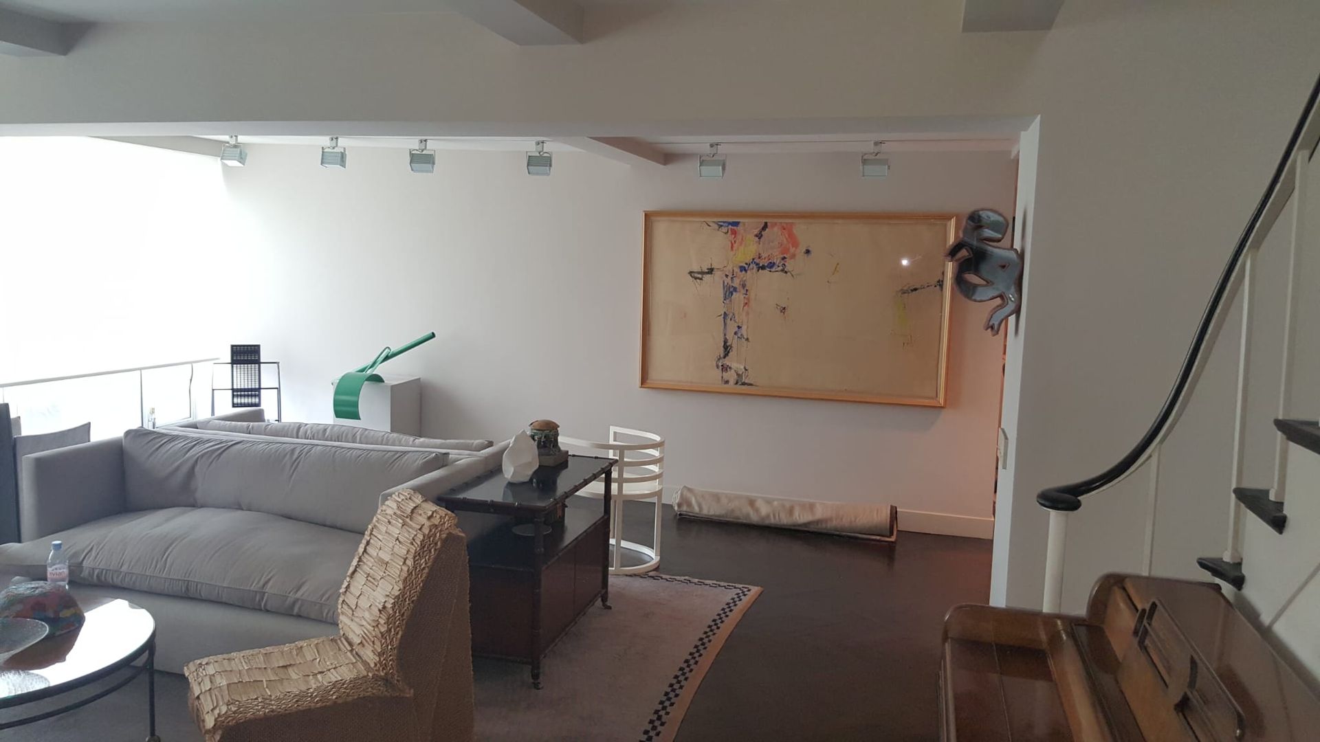 A living room with a couch, chair, table and stairs.