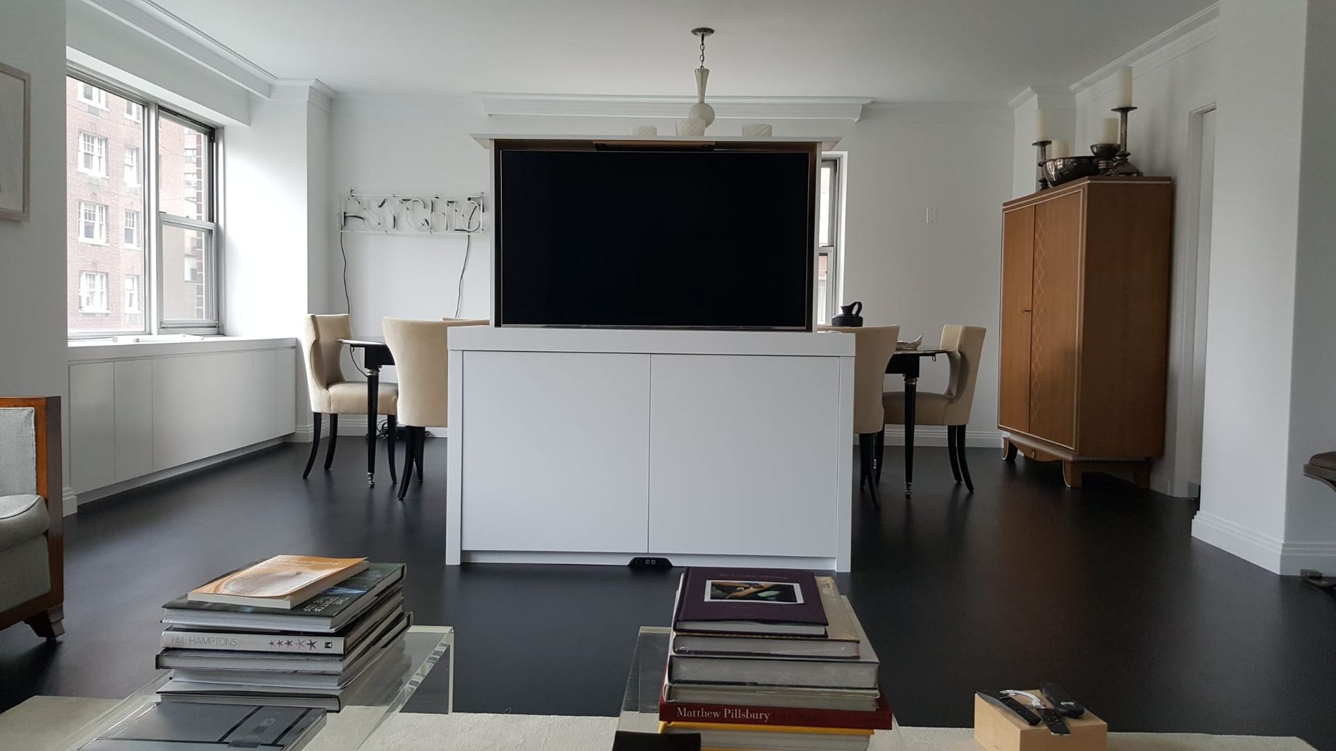 A living room with a flat screen tv behind a white cabinet