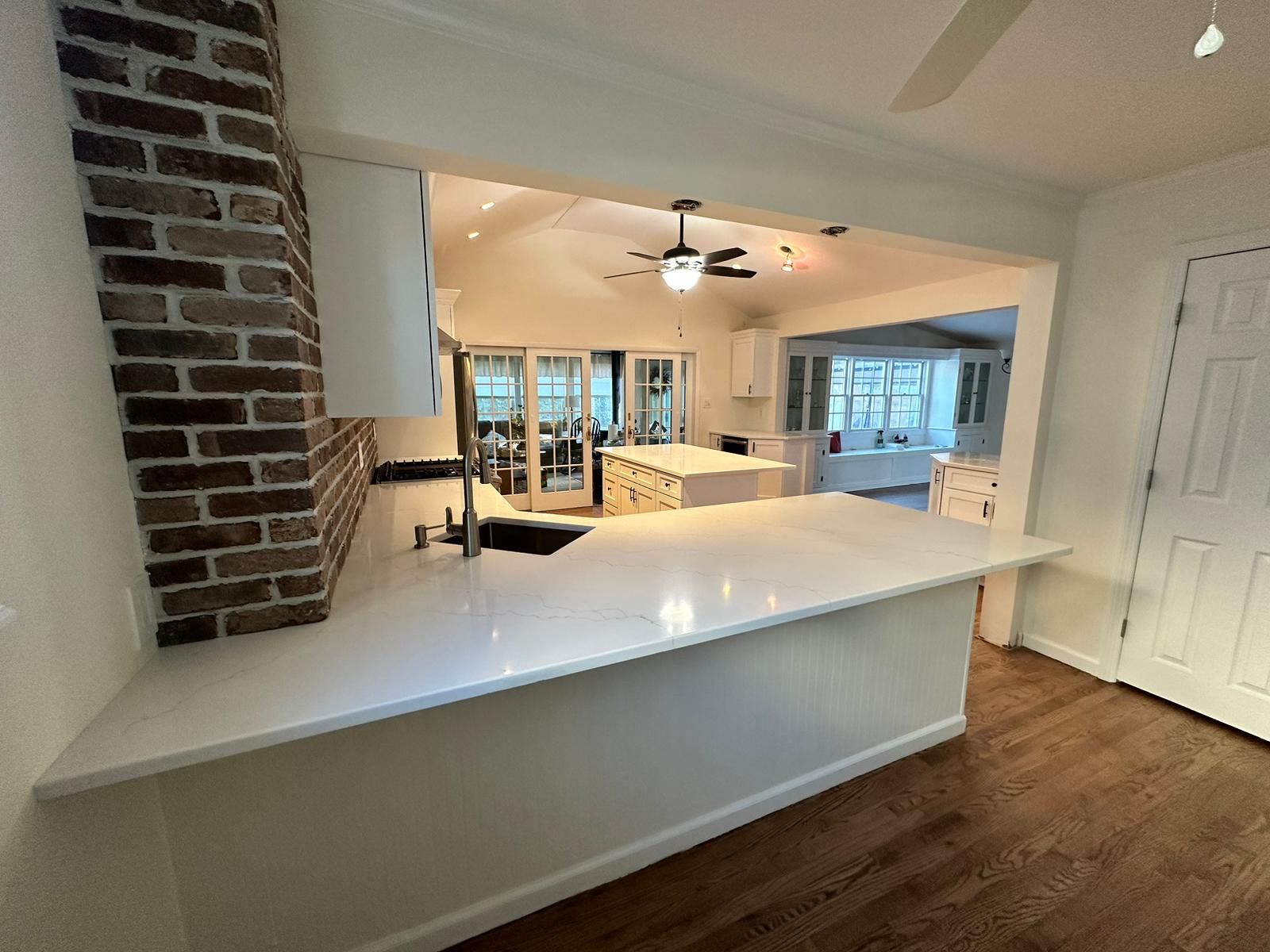 A kitchen with a brick chimney and a ceiling fan.