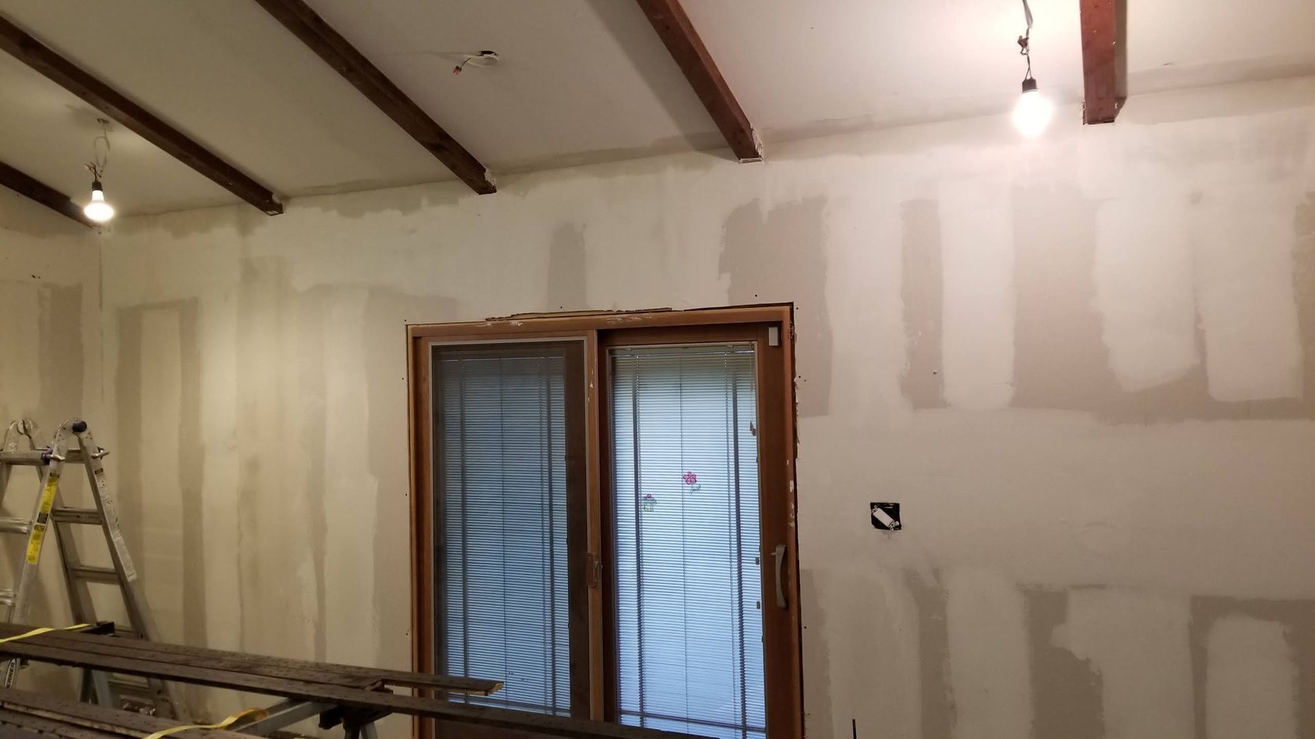 A room with a sliding glass door and a ladder in it.