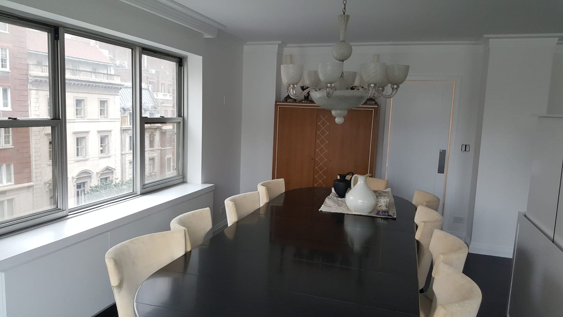 A dining room with a long table and chairs and a chandelier.