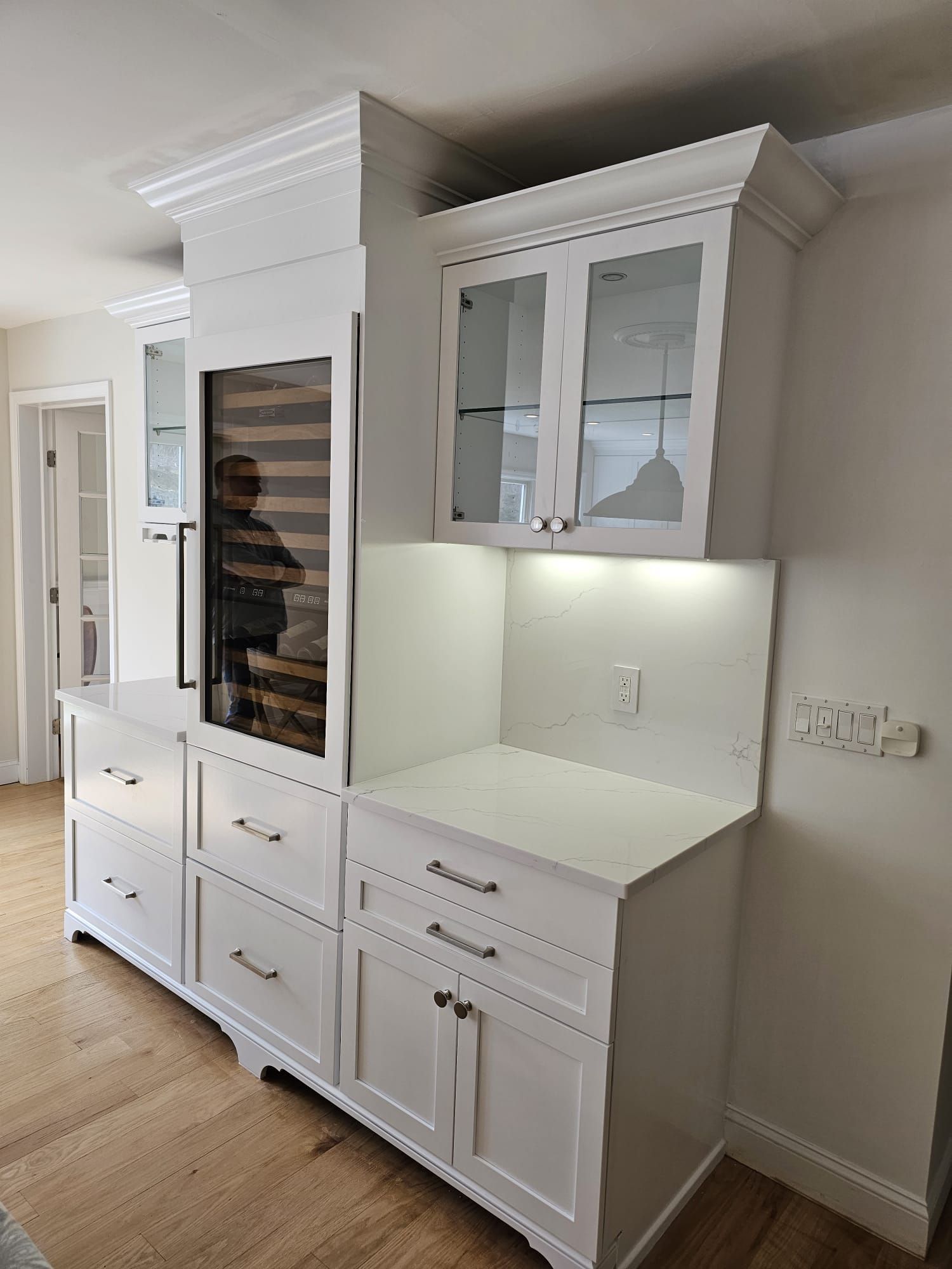 A kitchen with white cabinets and a wine cooler.