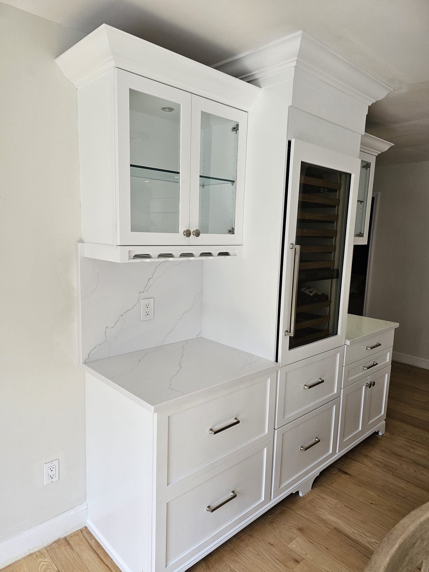 A kitchen with white cabinets, drawers, and a refrigerator.