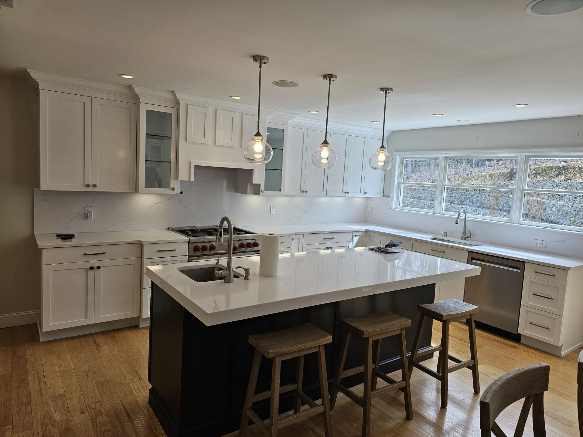 A kitchen with white cabinets, stainless steel appliances, and a large island.