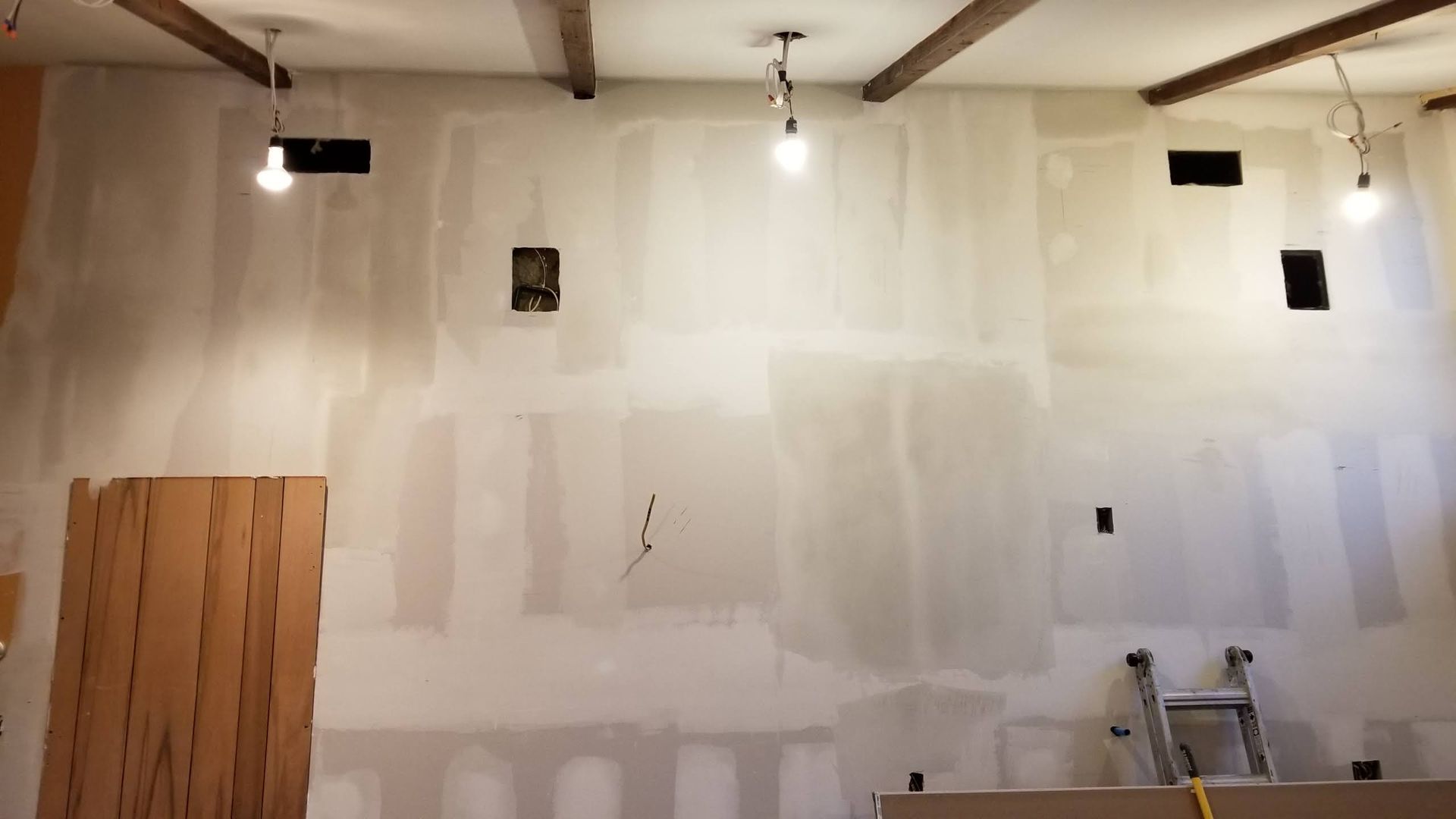 A room with a ladder and lights hanging from the ceiling.