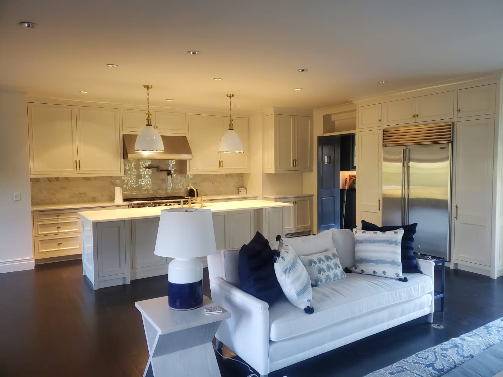 A living room with a white couch and a kitchen in the background