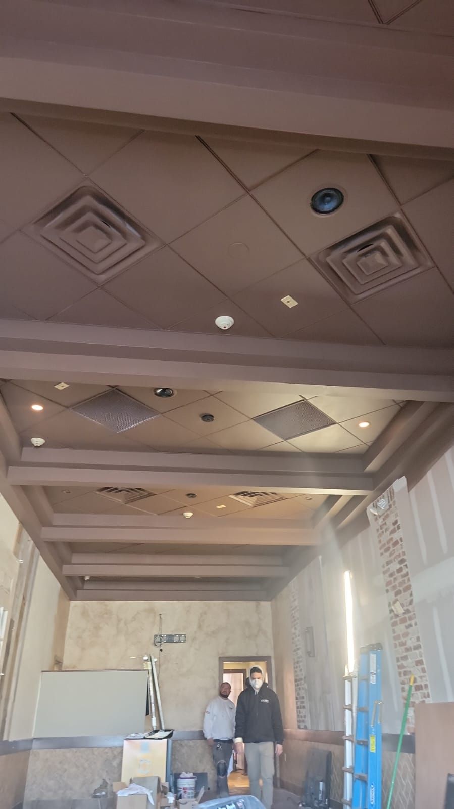 Two men are standing in a room with a ceiling that is being remodeled.