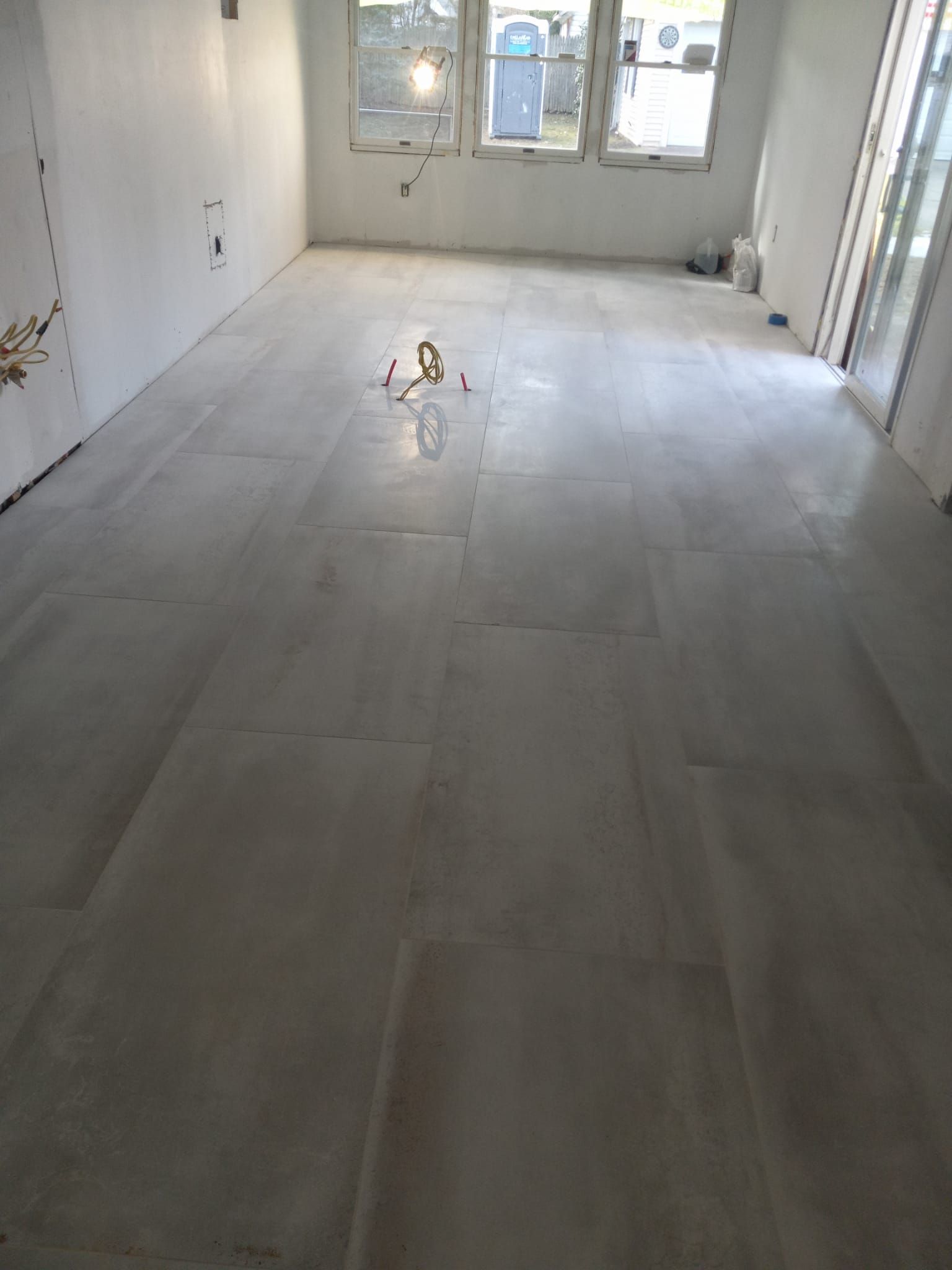 A large empty room with a tiled floor and white walls.