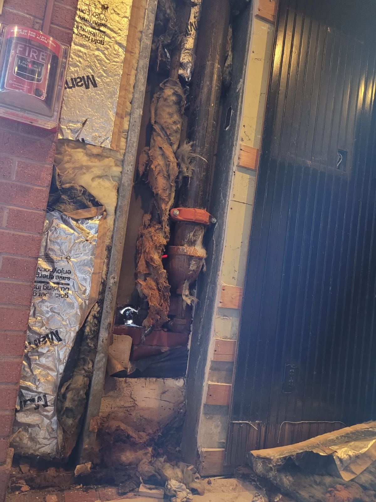 A brick wall with a lot of pipes coming out of it.