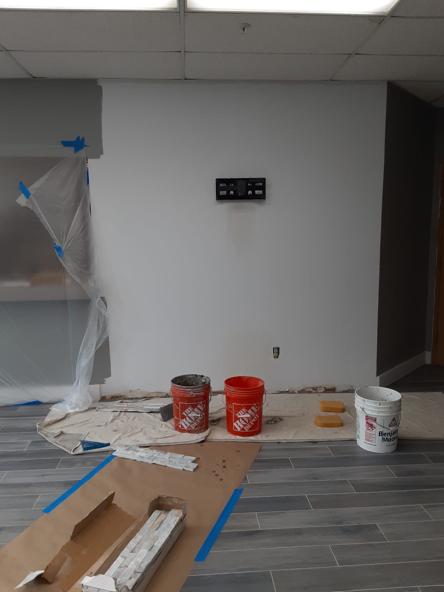 A room that is being painted with buckets of paint on the floor.