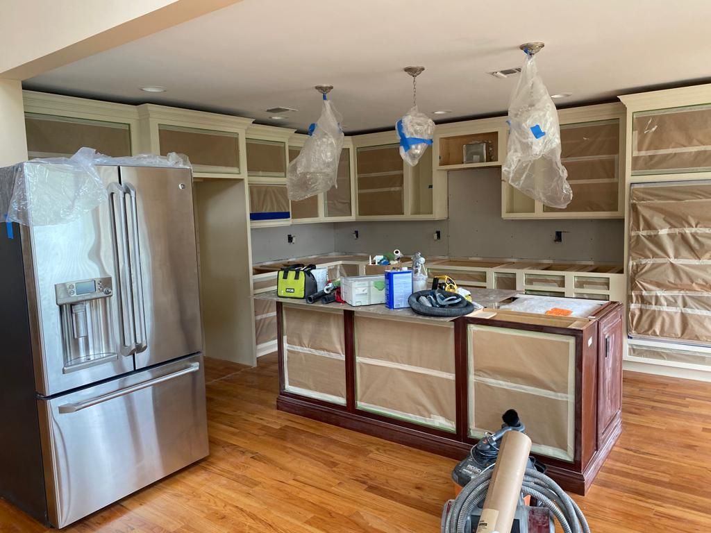 A kitchen under construction with stainless steel appliances and wooden floors.