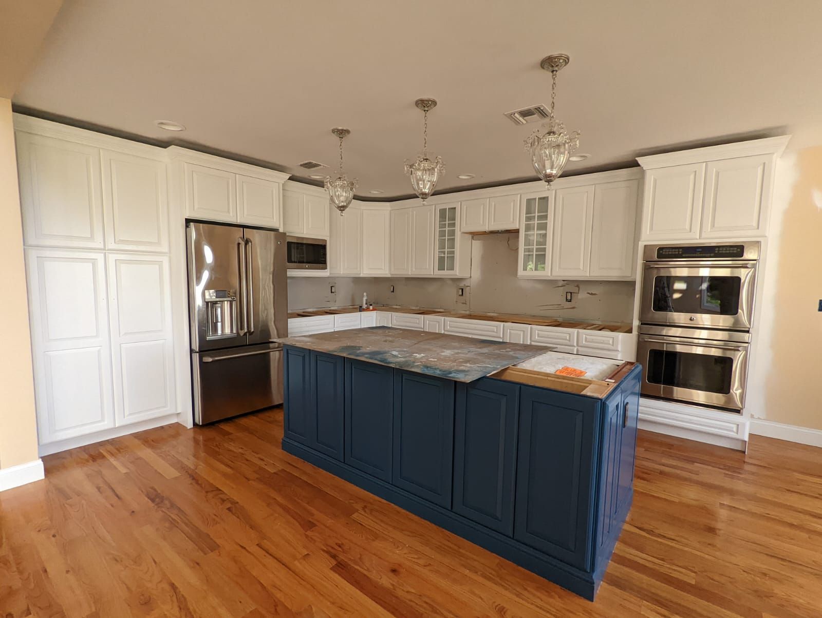 A kitchen with white cabinets and stainless steel appliances and a large blue island.