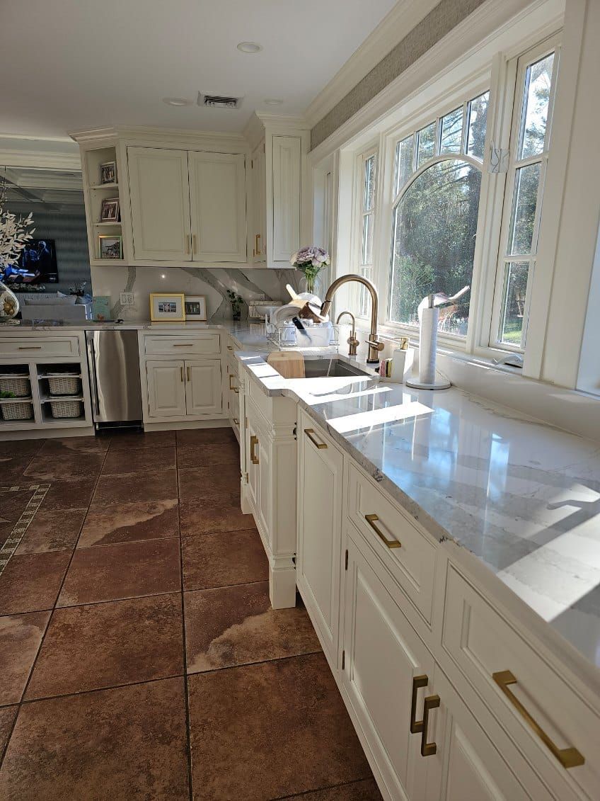 A kitchen with white cabinets, a sink, and a window.