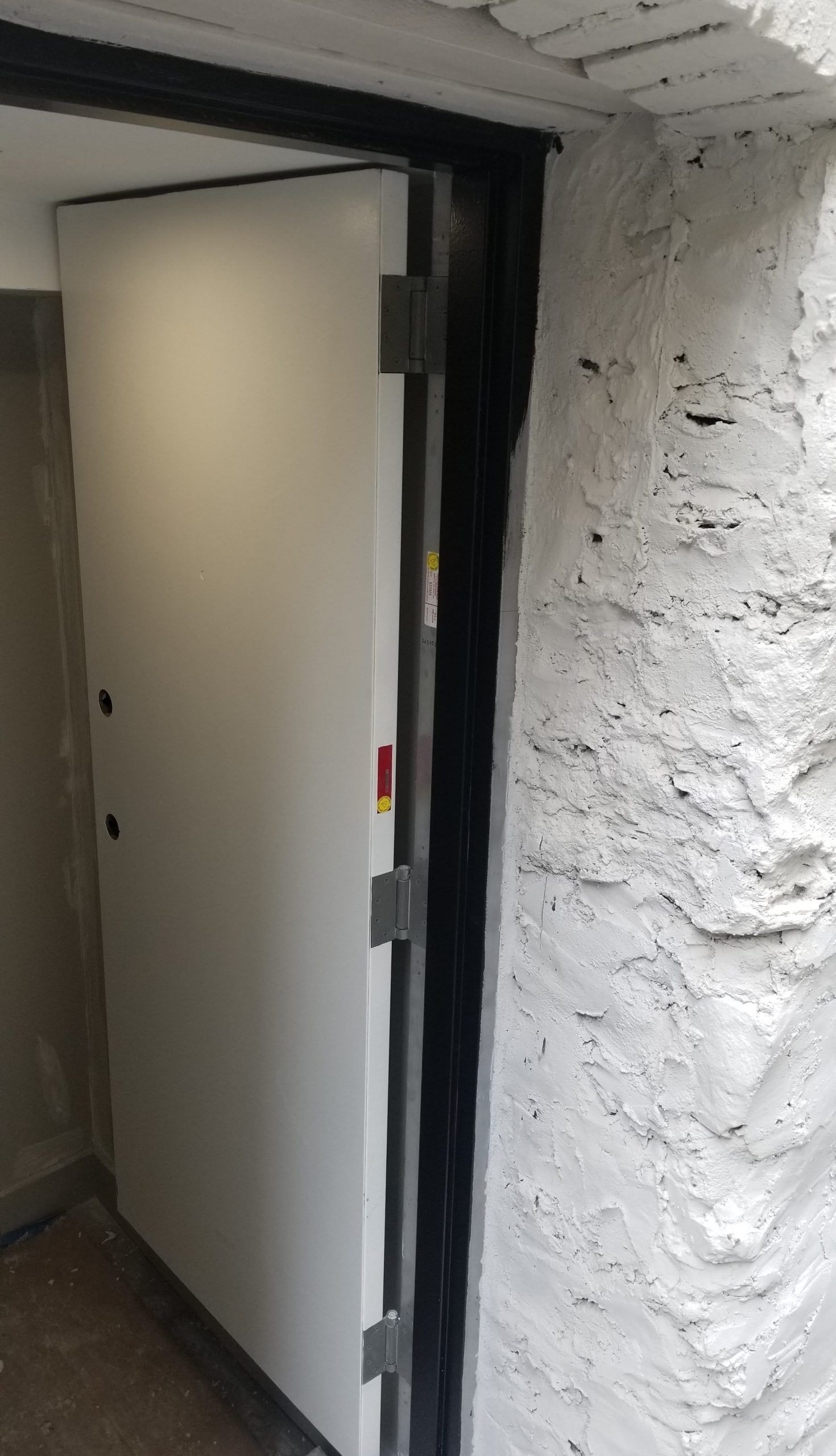 A white door is open in a room with a white wall.