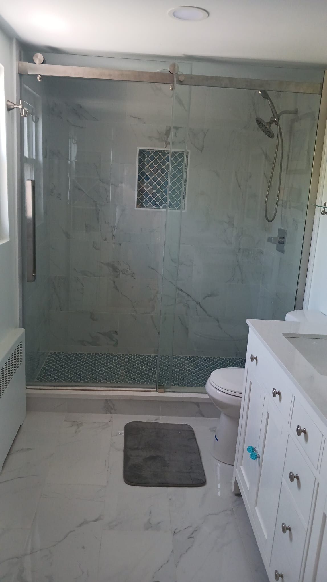 A bathroom with a walk in shower, toilet, sink and vanity.