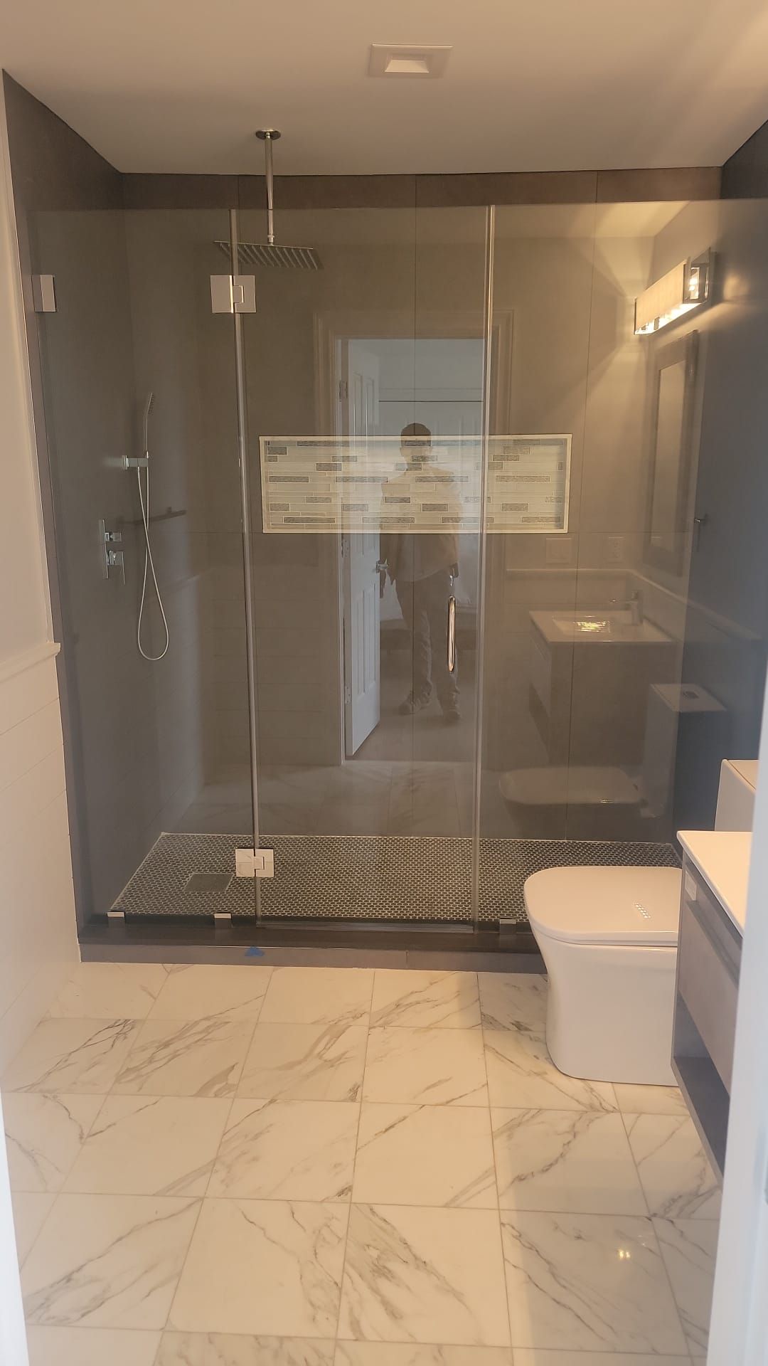 A bathroom with a walk in shower, toilet and sink.