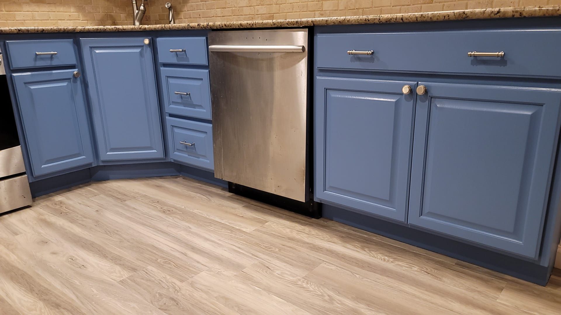 A kitchen with blue cabinets and a stainless steel dishwasher.