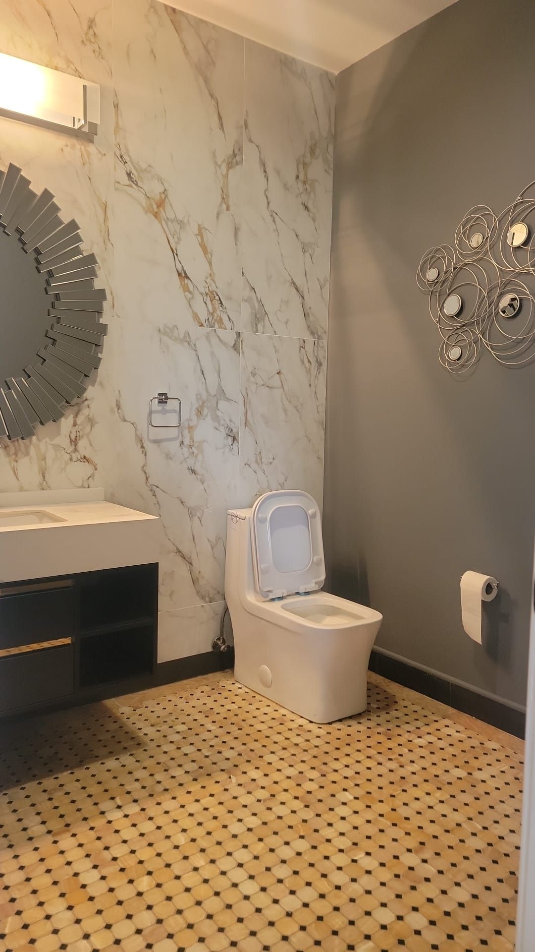 A bathroom with a toilet, sink and mirror.