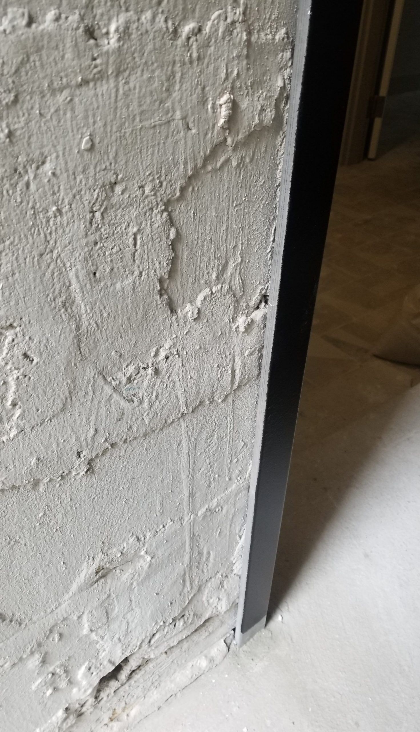 A close up of a concrete wall in a room with a door.