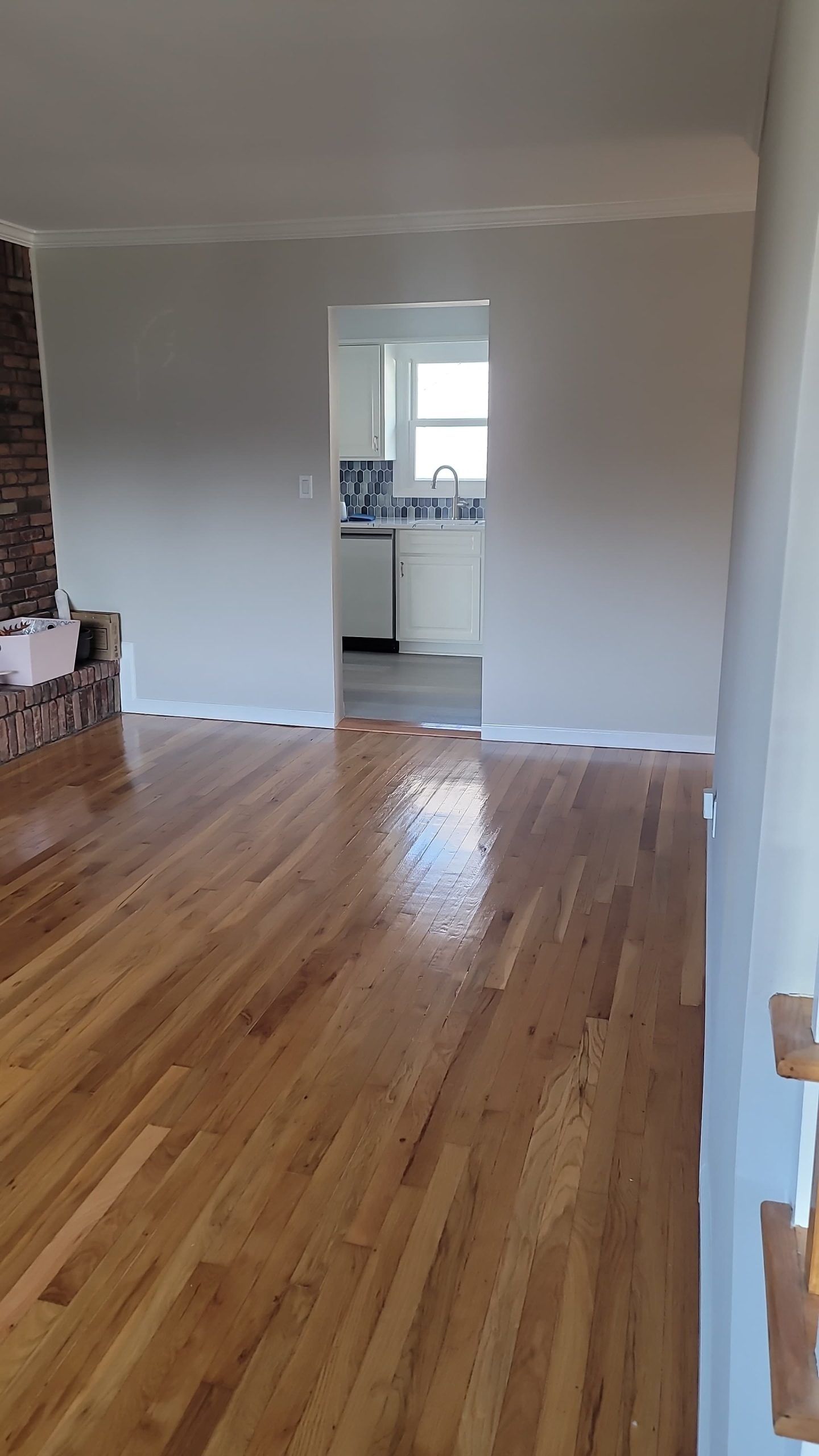 An empty living room with hardwood floors and a fireplace.