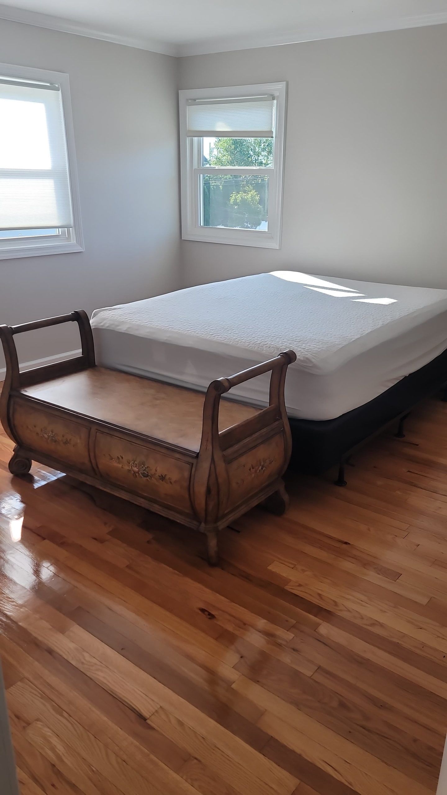 A bedroom with a bed, bench, and window.