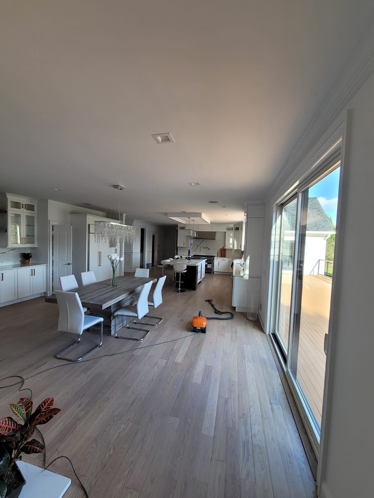A large living room with a table and chairs and a vacuum cleaner.