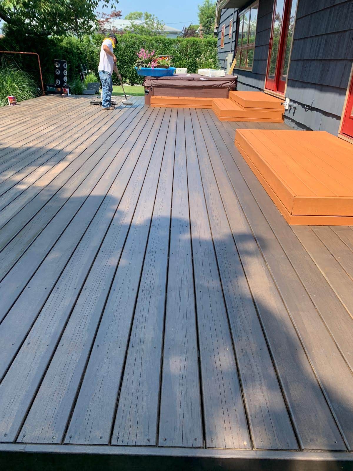 A man is standing on a wooden deck next to a house.