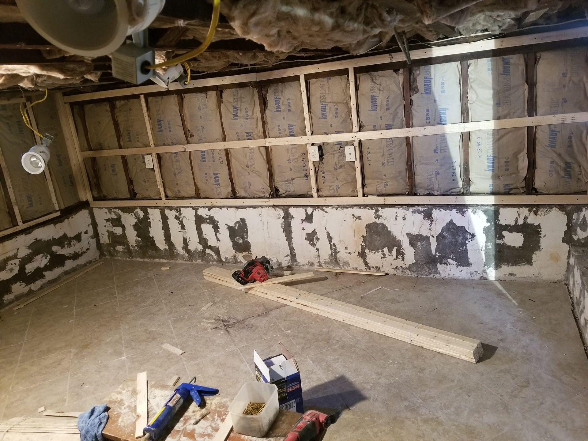 A basement with a lot of insulation on the walls and a lot of tools on the floor.