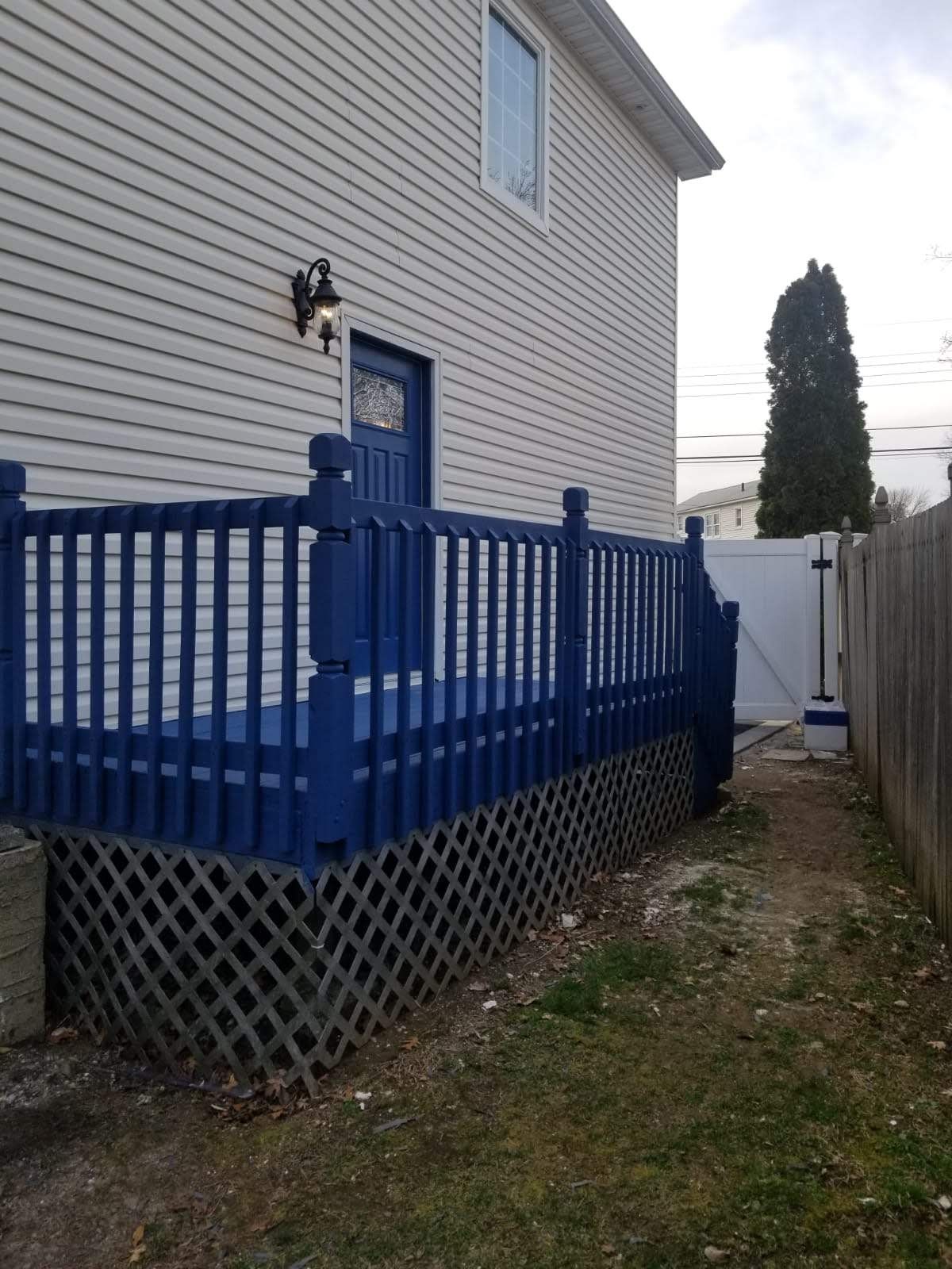A white house with a blue deck and fence